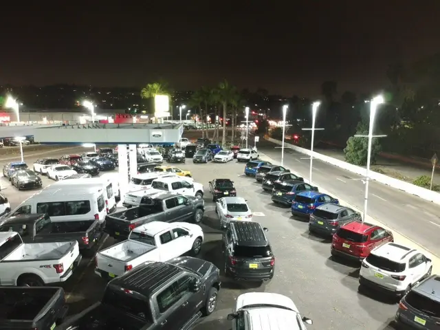 LED pole lights over parked trucks on the Mossy Ford sales lot in Pacific Beach at night